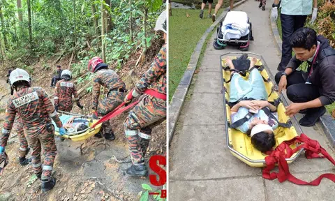 Firefighters carrying the woman on a stretcher down a wooded area in Kanching Forest Eco Park on June 6.