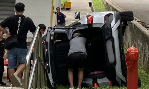 Car flips onto its side next to HDB block in Bedok, believed to have skidded