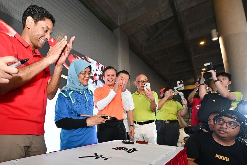 Former president Halimah Yacob writing Chinese calligraphy at the Peace and Prosperity Singapura SG60 Walkathon at Marina Barrage on June 1.