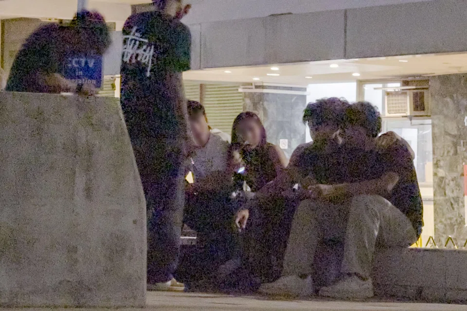 A man and a woman (seated, left) sharing a vape outside Drip on Aug 23. At least three vapes can be seen among the group.