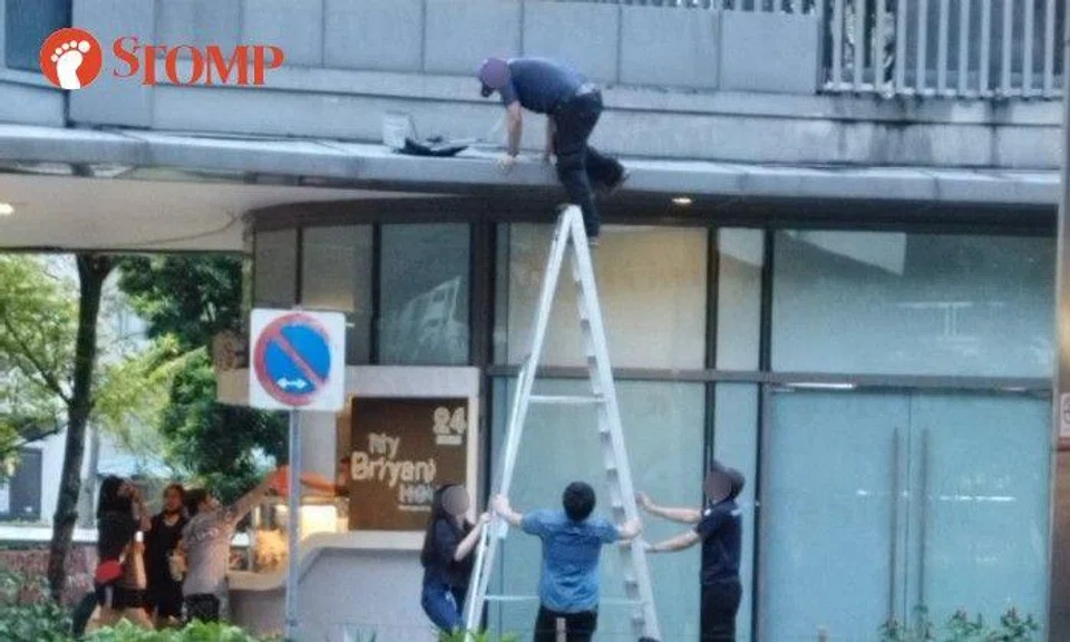 Stomper Mikael shared a photo of the man on the A frame ladder being held by three other people near the My Briyani House outlet.