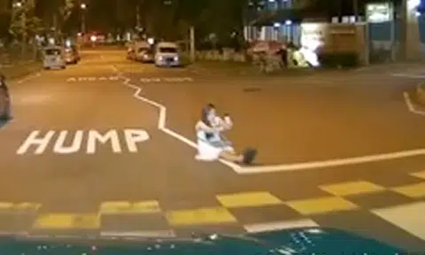 Woman risks her life by sitting in the middle of the road to take a selfie