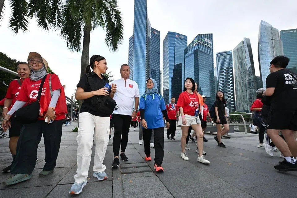 Former president Halimah Yacob interacting with her former security officer Lim Hwee Yi (in black top) while taking part in the Peace and Prosperity Singapura SG60 Walkathon on June 1.