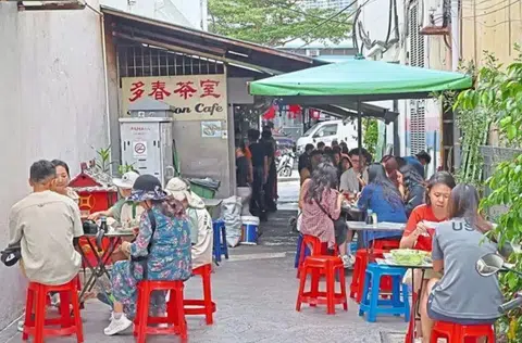 Patrons enjoying steamed bread with kaya, half boiled eggs and local coffee at a 70-year-old coffee shop in George Town.