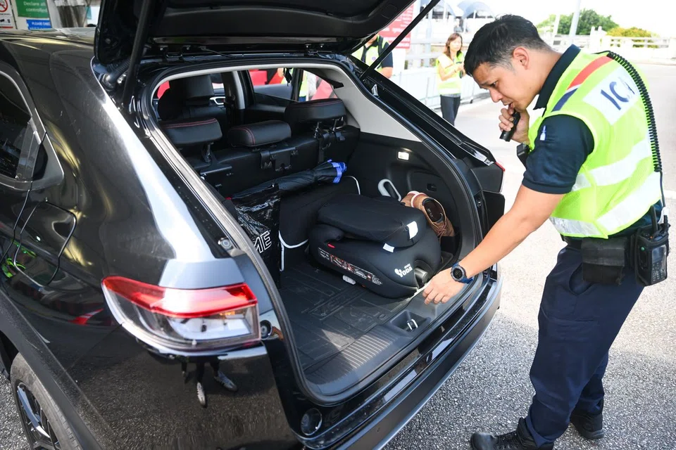 An ICA officer searching the boot of a car at Tuas Checkpoint on Aug 22.