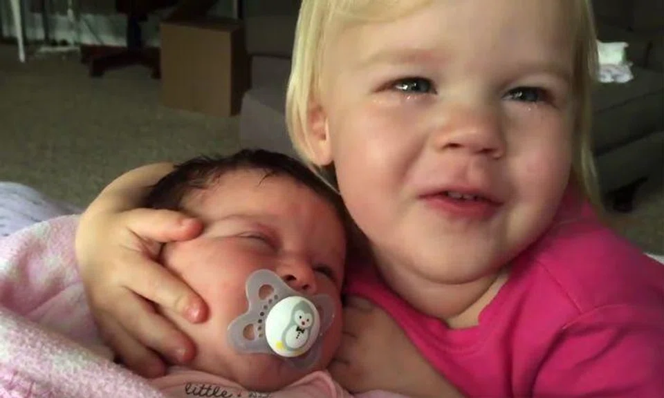 Toddler wakes up grumpy -- but everything changes when she sees mum holding baby sister