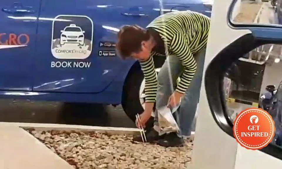 Female Silvercab driver picks up litter with chopsticks while in queue at T4 taxi stand