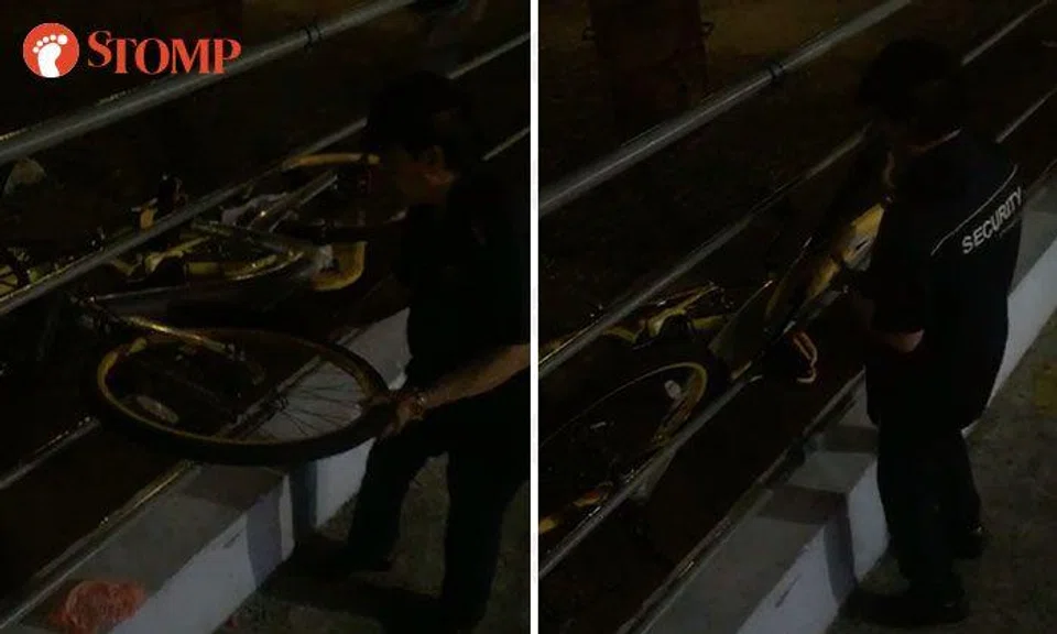 Man in security uniform shoves oBike between platform railings and lets it fall