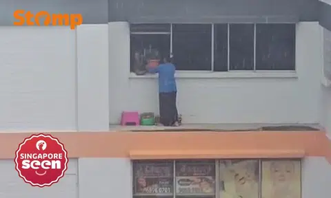 woman stands on parapet during downpour in bukit batok