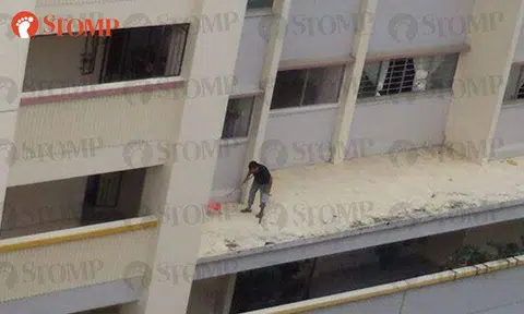 Man stands on ledge to do cleaning at Yishun block