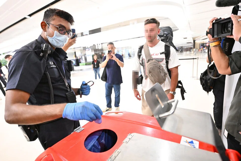 An ICA officer disposing of a vape after confiscating it from a traveller at Changi Airport Terminal 1 on Aug 22.