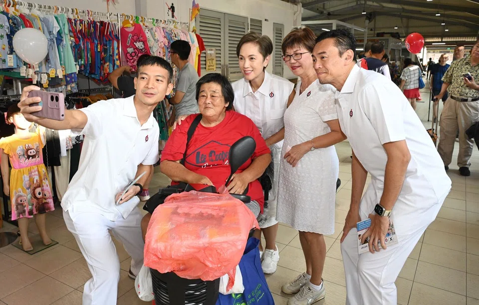 PAP Jalan Besar candidates (from left) Shawn Loh, Josephine Teo, Denise Phua and Wan Rizal taking a wefie with Ms Tan Leng Hong (in red) during the walkabout at Upper Boon Keng Market on April 27.