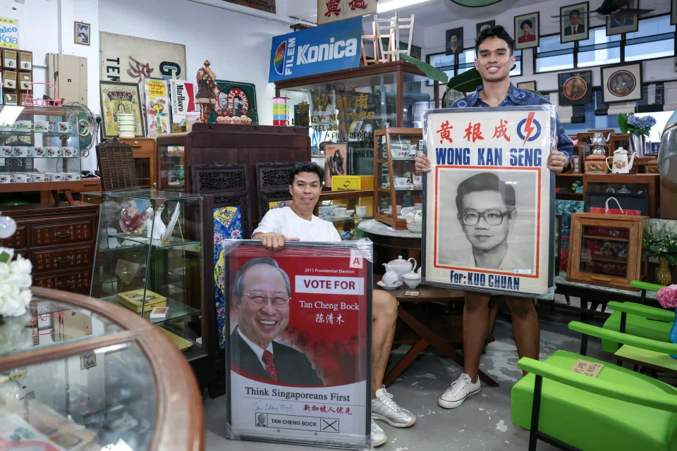 Mr Wak Sadri (left), owner of Treasure At Home, with his son Emyr Uzayr, holding election posters of Dr Tan Cheng Bock and Mr Wong Kan Seng at Treasure At Home Vintage Store at 80 Playfair Road. 