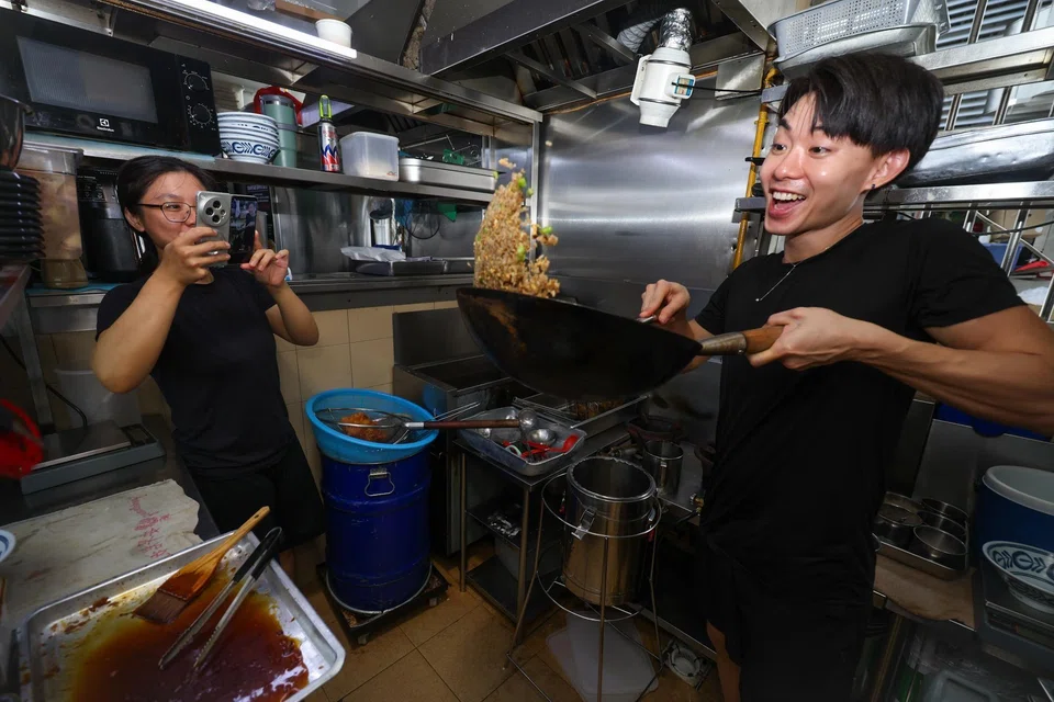 Stall owner Kenny Ngoo, being filmed by stall assistant Grace Aw, at his stall, Salt, at Old Airport Road Food Centre.