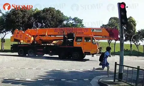 Student dashes across road while using phone -- and nearly gets hit by mobile crane