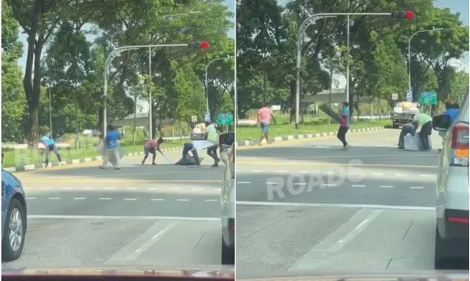 Eight different individuals can be seen running towards the pile of items on the road and scrambling to clear it before the traffic light turns green. 