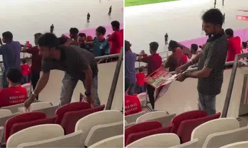 man picks up flyers from the ground during sg bangladesh football match