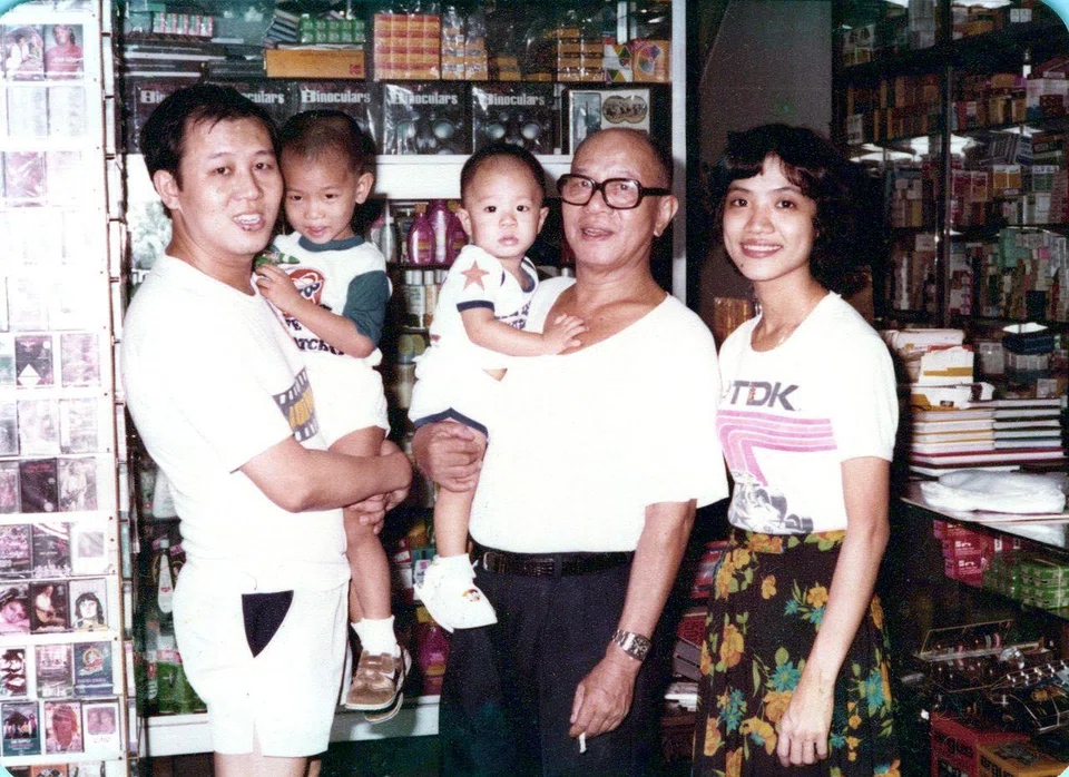 A family photo taken at Joo Ann Foh’s original shop in Holland Avenue in the 1980s. A section of the shop carried photography-related products, while another section offered daily provisions. Seen here are business founder Ng Chin Wah (with glasses), second-generation owner Paul Ng and his wife Irene Mah, and the couple’s young sons Kenneth Ng (left) and Adam Ng.