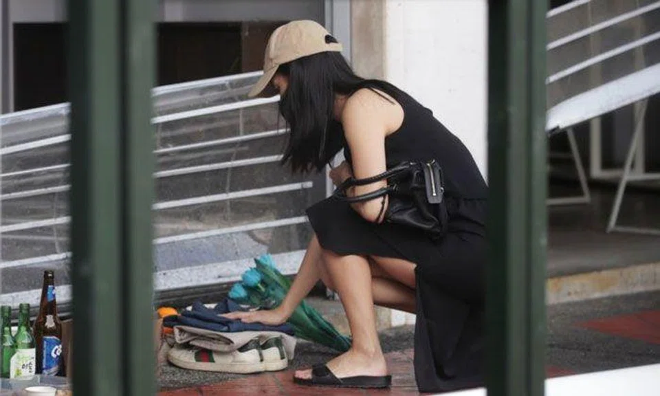 A woman, who said she was a family member of one of those who died, entered the shop with a bouquet of blue flowers. ST PHOTO: GIN TAY