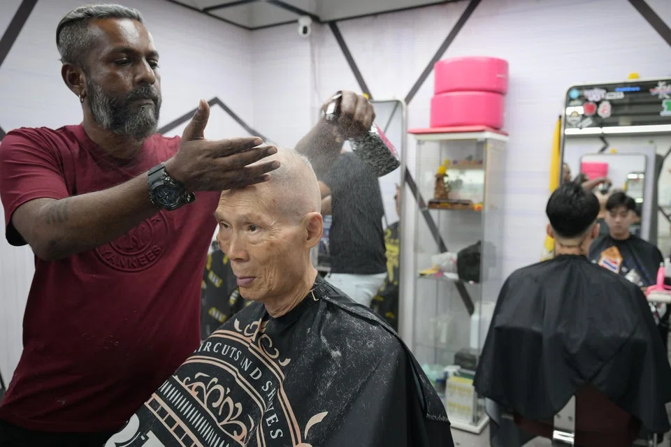 Barber Vishnu Vijendran cutting Mr Kwek Tee Nee's hair. 