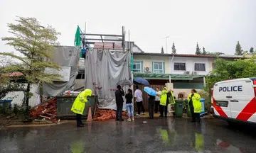 Police officers and investigators at Jalan Usaha after bricks placed on a completed canopy fell onto a worker at a house construction site on May 16.