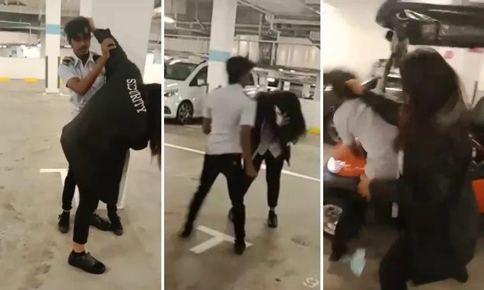 The video shows a woman in a "security" jacket and a man in a security guard uniform pulling each other's hair.