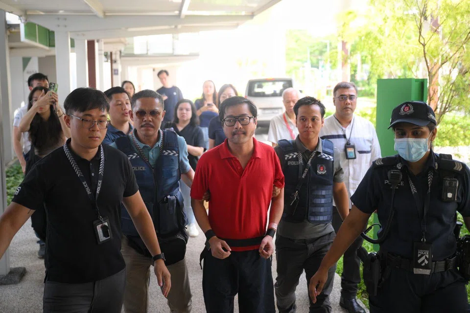 Accused Lim Yuen Li (in red polo shirt) being escorted by police officers on July 4, 2025, back to the Fernvale Road flat where the incident took place.