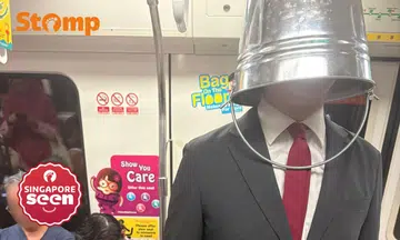 Man wearing bucket over head on MRT