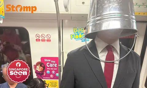 Man wearing bucket over head on MRT