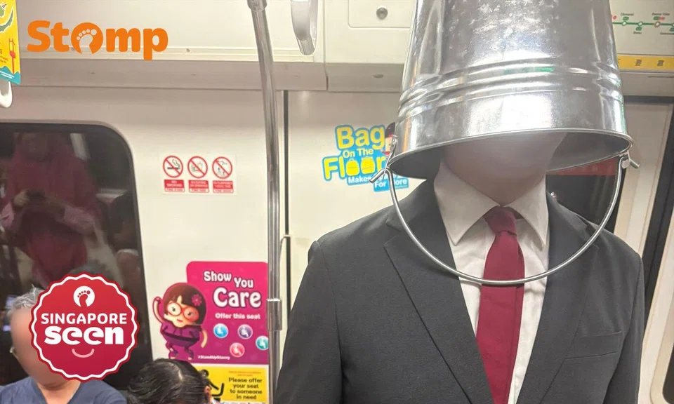 Man wearing bucket over head on MRT