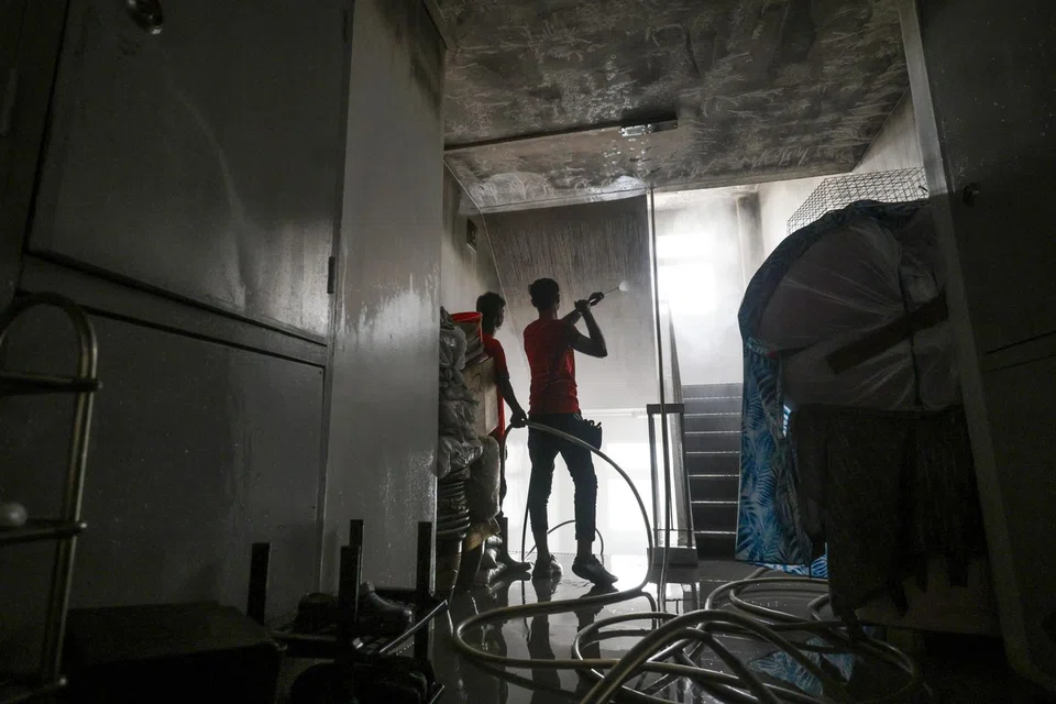 Workers cleaning the layer of soot at the staircase and common area at Block 5, Holland Close on June 20.