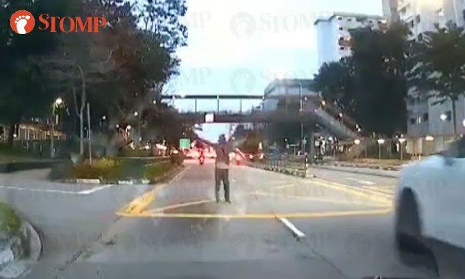 Man staggers onto road and raises arms at oncoming car at Bedok North Road