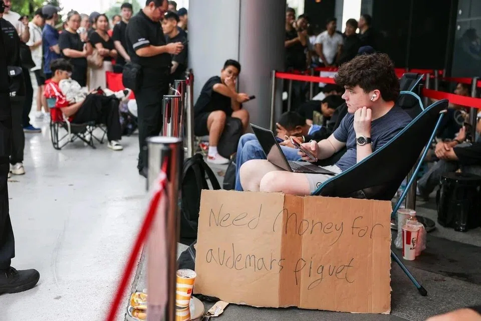 Mr Keegan Darmine, 16, a student from Singapore American School, sitting beside a sign reading ‘Need money for Audemars Piguet’ while queueing outside Ion Orchard.