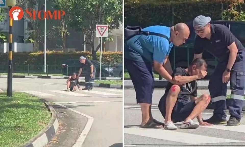 Injured man sits at pedestrian crossing, holding vape and shaking uncontrollably as passers-by help get him off road