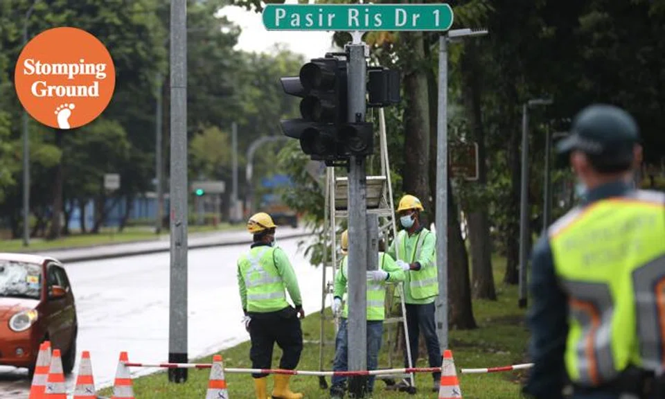 Workers disassembling the traffic light lantern to replace the current traffic lights with red-amber-green arrows, to prevent the discretionary right turn at a junction at Pasir Ris Dr 1 on Dec 31, 2021.