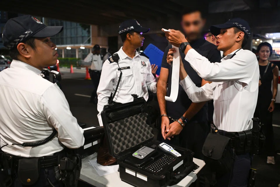 A Traffic Police officer explaining to a 43-year-old man the result of the Handheld Breath Evidential Analyser test that he failed.