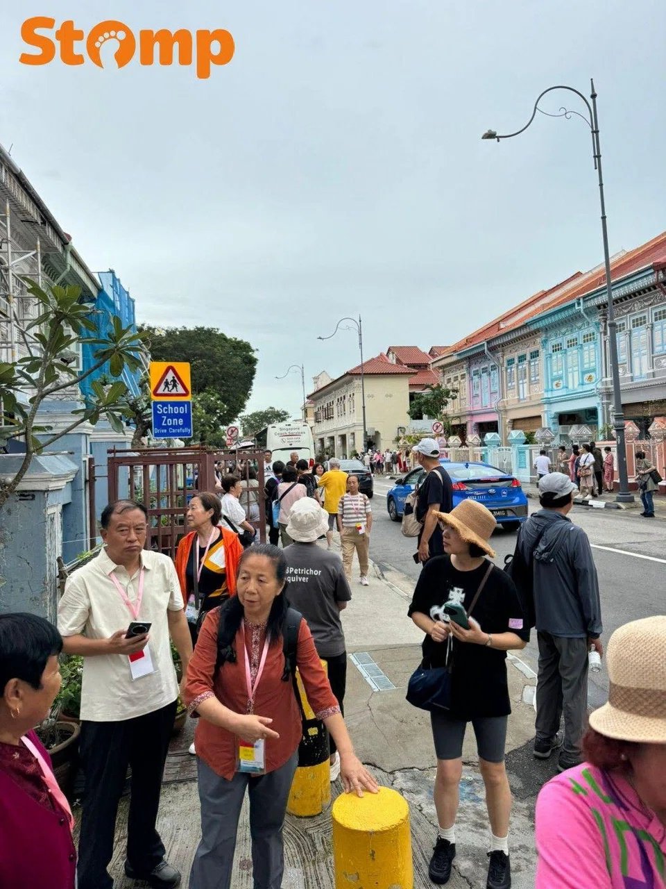 Sightseers crowding the walkways beside the iconic brightly-coloured Peranakan shophouses.