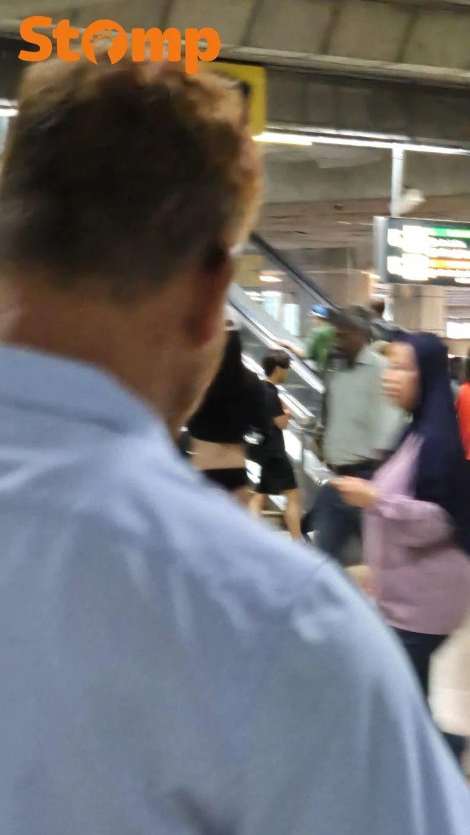 Individual wearing skimpy black shorts and a midriff-revealing cropped top at the busy Jurong East MRT station.