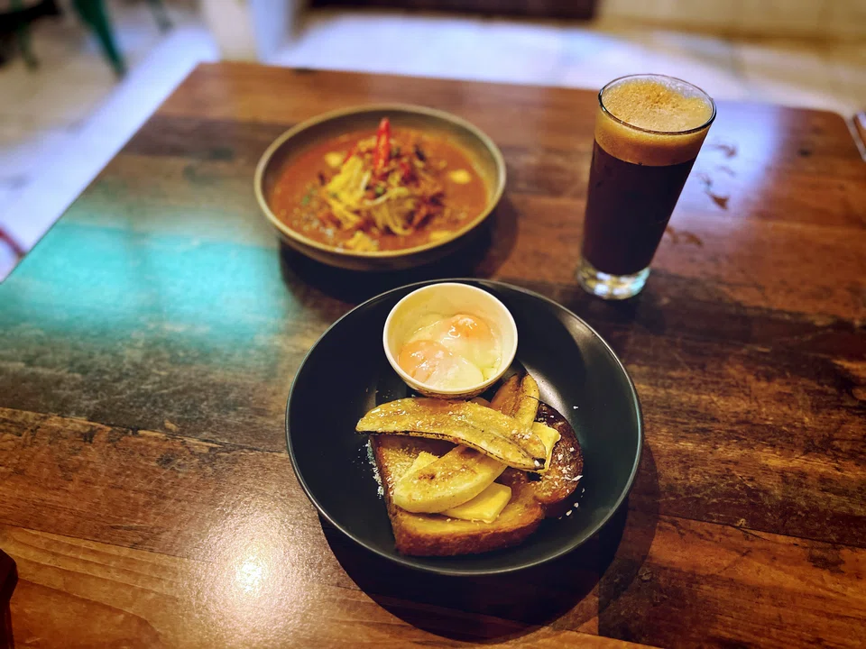 A plate of grilled toast with banana slices, mee rebus with beef slices and a cup of iced Kopi C in LeLA. Credit: HARITH MUSTAFFA