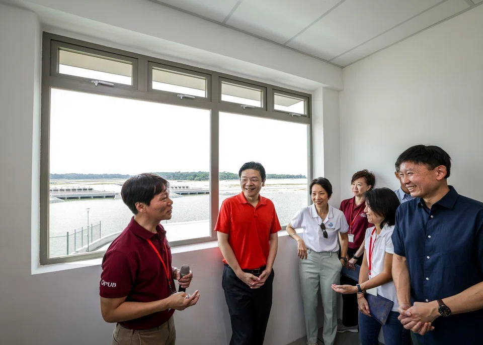 PM Lawrence Wong (in red) visiting the completed polder at Pulau Tekong on Sept 8. He was accompanied by National Development Minister Chee Hong Tat (right), Minister for Sustainability and the Environment Grace Fu (3rd from left) and Senior Parliamentary Secretary for Sustainability and the Environment Goh Hanyan (2nd from right).