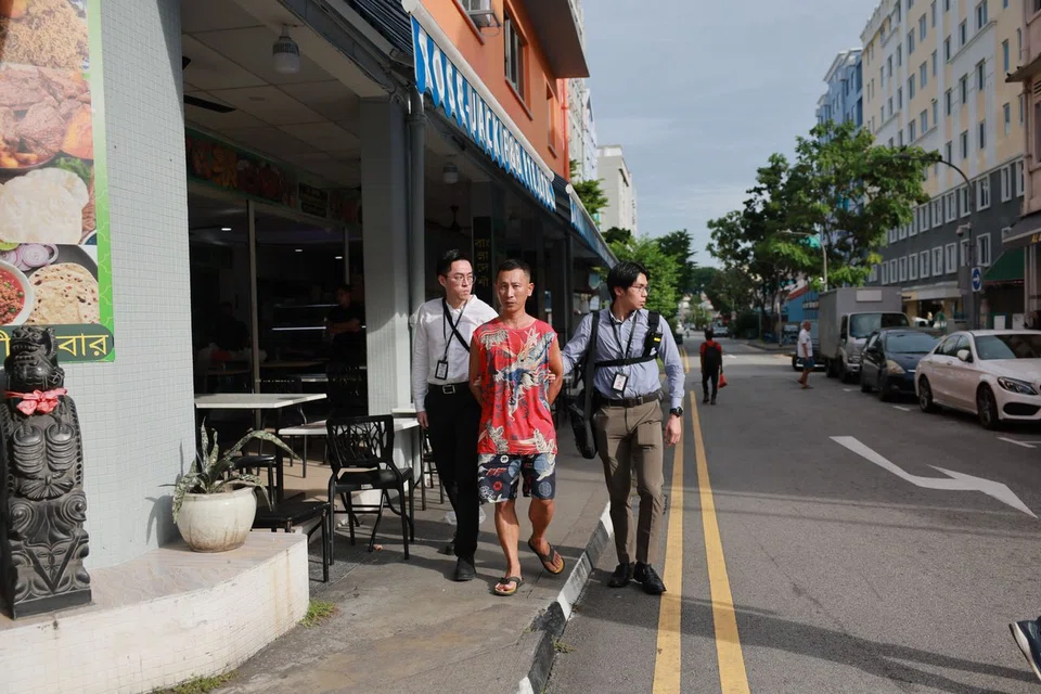 Xiao being taken back to the scene in Geylang Lorong 20 by CPIB officers on July 17.