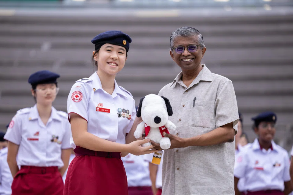 Alva Wong (left), an RGS student, receiving a Snoopy plush dressed in a Singapore Red Cross vest from Mr Benjamin William, CEO of the Singapore Red Cross.