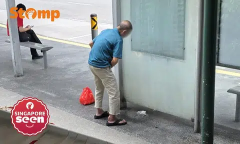 man pees at bus stop outside Sembawang MRT station