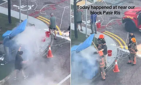 2 men put out a fire billowing out of a big blue bin at the foot of a block in Pasir Ris.