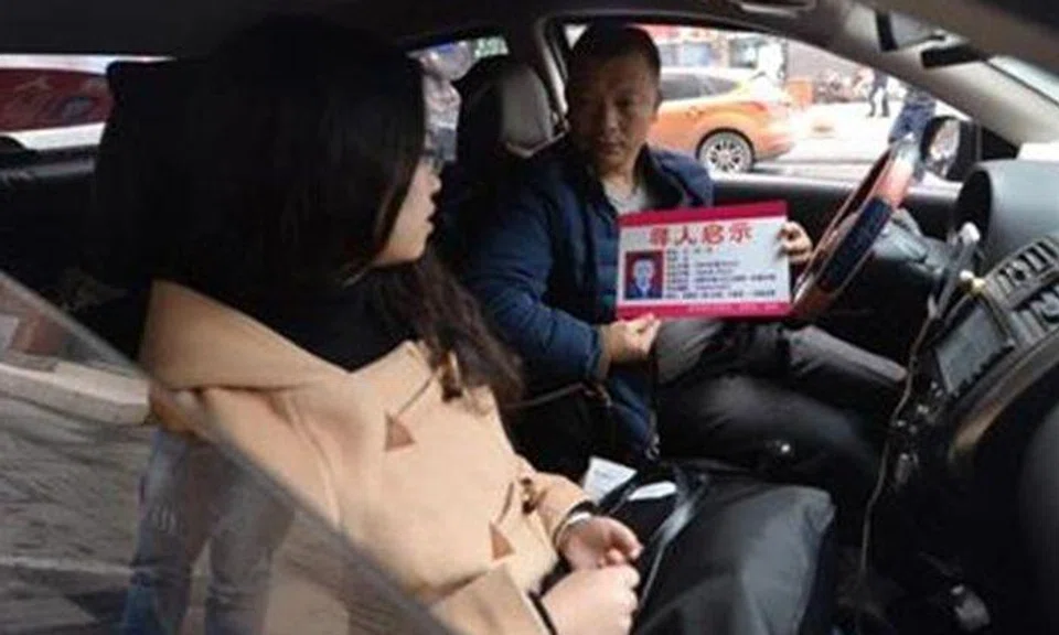 Wang Qingming shows a passenger the card with details about his missing daughter.