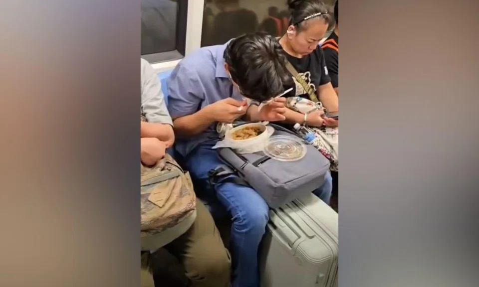 man eating takeaway meal on MRT