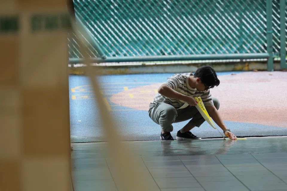 An election official pasting stickers on the ground during the setting up of the polling station at Bendemeer Primary School on the eve of Polling Day on May 2.