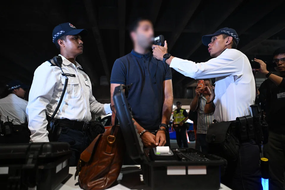 Traffic Police officers screening a 43-year-old motorist using the Handheld Breath Evidential Analyser in Upper Cross Street on Sept 20.