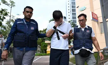 Police officers brought 28-year-old Davin Lian Ke Xiang, who is accused of throwing eggs at police cars, to the crime scene in Punggol on March 31.