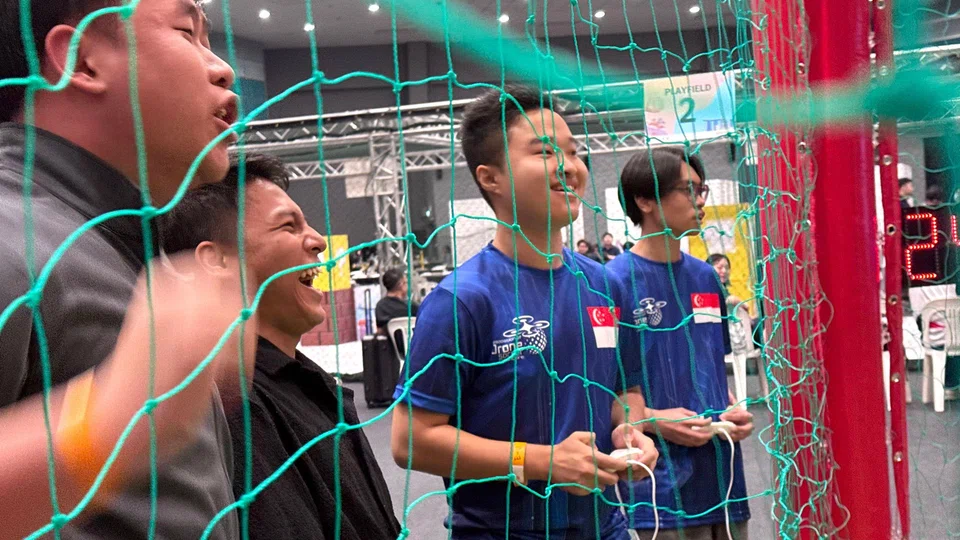 Mr Zhu Zixuan (centre) celebrates with his team after scoring a goal during a match. 